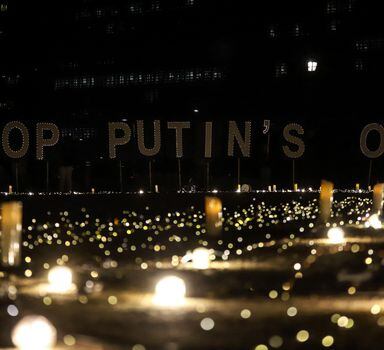 A signs reads "Stop Putin's oil" during a vigil for Ukraine near the European Union (EU) headquarters in Brussels, on March 22, 2022. - Demonstrators call on EU leaders to impose a full ban on Russian fuels. (Photo by Valeria Mongelli / AFP)