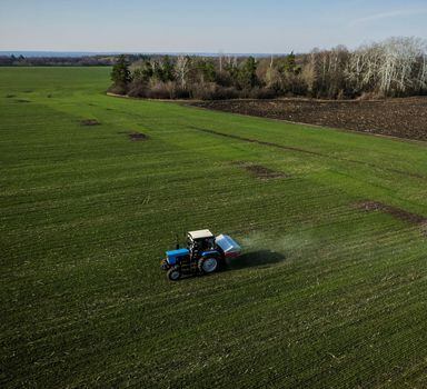 FILE PHOTO: An aerial view shows a tractor spreading fertiliser on a wheat field near the village of Yakovlivka after it was hit by an aerial bombardment outside Kharkiv, as Russia's attack on Ukraine continues, April 5, 2022. Picture taken with a drone. REUTERS/Thomas Peter/File Photo