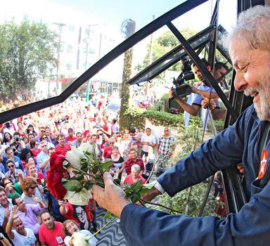 O ex-presidente Luiz Inácio Lula da Silva aparece na janela enquanto partidários do PT realizam um abraço coletivo no prédio do Instituto Lula, na , zona sul da capital