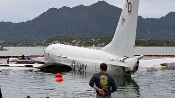 Contractors place inflatable bags under a U.S. Navy P-8A in Kaneohe Bay, Hawaii, Friday, Dec. 1, 2023, so they can float the aircraft over the water and onto land. The Navy plans to use inflatable cylinders to lift the jet off a coral reef and then roll it over to a runway to remove the plane from the ocean where it crashed the week before. (AP Photo/Audrey McAvoy). Foto: AP Photo/Audrey McAvoy