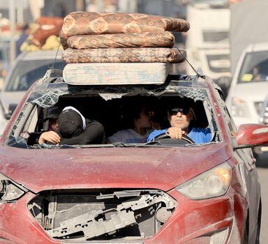 Riding in a damaged vehicle a Palestinian family flees with hundreds of other following the Israeli army's warning to leave their homes and move south before an expected ground offensive, in Gaza City on October 13, 2023. Palestinians carried belongings through the rubble-strewn streets of Gaza City on October 13, in search of refuge as Israel's army warned residents to flee immediately before an expected ground offensive in retaliation against Hamas for the deadliest attack in Israeli history. (Photo by Mahmud HAMS / AFP)