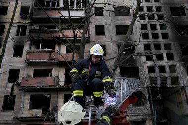 Bombeiro ucraniano entrega uma foto retirada de um prédio bombardeado pelas forças russas em Kiev em 14 de março 