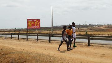 Angolanas caminham no canteiro central da Avenida Fidel Castro, em Luanda, dominada pela presença de indústrias e empresas chinesas. Foto: Felipe Frazão