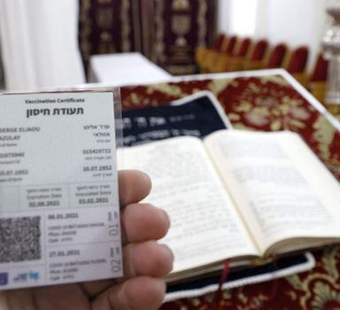 Um devoto judeu exibe seu "cracháverde", um cartão dado a indivíduos que foram totalmente vacinados, em uma sinagoga na cidade costeira israelense de Netanya.