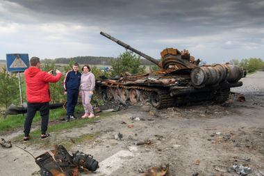 Pessoas posam para uma foto em frente aos destroços de máquinas militares russas destruídas durante a invasão russa da Ucrânia, na vila de Rusaniv, região de Kiev, Ucrânia, em 25 de abril de 2022