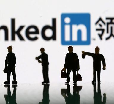 Small toy figures are seen between displayed U.S. flag and Linkedin logo in this illustration picture, August 30, 2018. To match Exclusive LINKEDIN-CHINA/ESPIONAGE  REUTERS/Dado Ruvic/Illustration