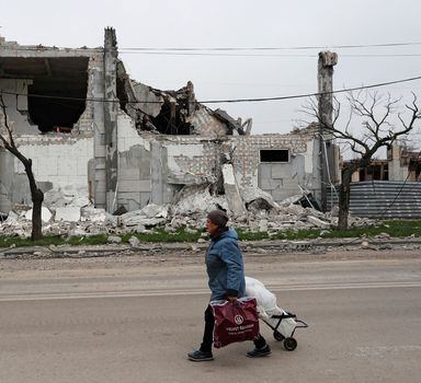 Mulher caminha pelas ruas destruídas de Mariupol