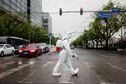 FILE PHOTO: A worker wearing a protective suit and carrying disinfection equipment crosses a road amid the coronavirus disease (COVID-19) outbreak in Beijing, China April 27, 2022. REUTERS/Carlos Garcia Rawlins/File Photo