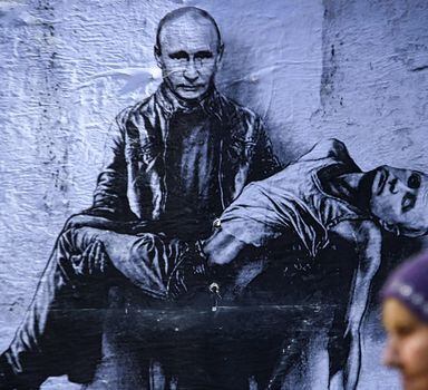 Mulher passa por mural que retrata o presidente Vladimir Putin segurando seu próprio corpo, em Sofia