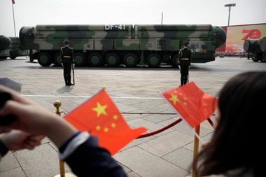 Cidadãos chineses balançam bandeiras do país durante uma parada militar em Pequim, China 
