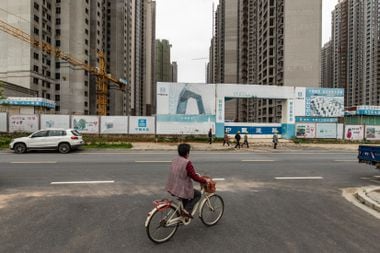 Mulher passa de bicicleta por um canteiro de obras em Nanchang