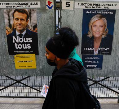 People walk past official campaign posters of French presidential election candidates Marine le Pen, leader of French far-right National Rally (Rassemblement National) party, and French President Emmanuel Macron, candidate for his re-election, displayed on bulletin boards in Paris, France, April 4, 2022. REUTERS/Gonzalo Fuentes