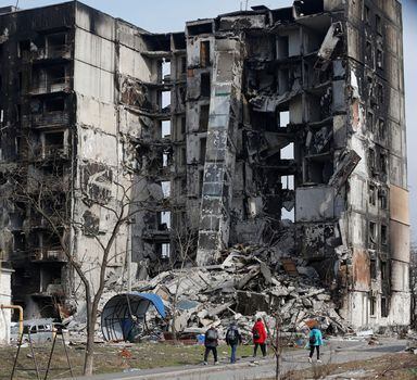 Local residents walk near an apartment building destroyed during Ukraine-Russia conflict in the besieged southern port city of Mariupol, Ukraine March 30, 2022. REUTERS/Alexander Ermochenko