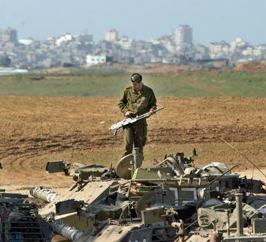 FILE - With a part of Gaza City seen on the background, an Israeli soldier stands on top of a military vehicle at a army staging area near Kibbutz Mefalsim on the edge of the nothern Gaza Strip on Jan. 20, 2005. Interim peace deals in the mid-1990s, several ill-fated U.S. peace initiatives by a string of American presidents failed, and the internationally recognized Palestinian Authority lost control of Gaza to Hamas in 2007. (AP Photo/Ariel Schalit)