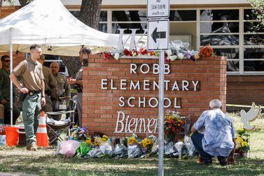 Um homem se ajoelha diante de um memorial de flores no local de um tiroteio em massa na Robb Elementary School em Uvalde, Texas