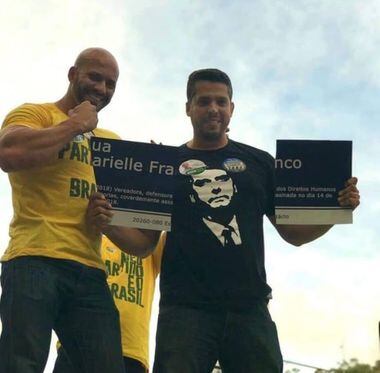 O deputado estadual Rodrigo Amorim segura a placa destruída que homenageava a vereadora do PSOL Marielle Franco ao lado de Daniel Silveira.