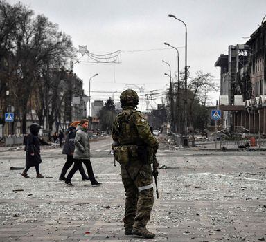 TOPSHOT - People pass by a Russian soldier in central Mariupol on April 12, 2022, as Russian troops intensify a campaign to take the strategic port city, part of an anticipated massive onslaught across eastern Ukraine, while Russia's President makes a defiant case for the war on Russia's neighbour. - *EDITOR'S NOTE: This picture was taken during a trip organized by the Russian military.* (Photo by Alexander NEMENOV / AFP)