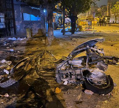 Burnt remains of a motorcycle lie in a street after communal violence in New Delhi, India, Sunday, April 17, 2022. Police in India's capital have arrested 14 people after communal violence broke out during a Hindu religious procession, leaving several injured. The suspects were arrested on charges of rioting and criminal conspiracy, among others, according to local media reports Sunday. (AP Photo/Arbab Ali)