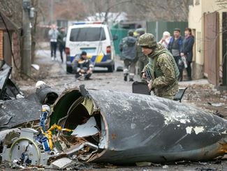 Um soldado do exército ucraniano inspeciona fragmentos de uma aeronave abatida, em Kiev, na Ucrânia;O governo encorajou moradores a fazerem coquetéis molotov, enquanto também aconselham outros a procurarem abrigo