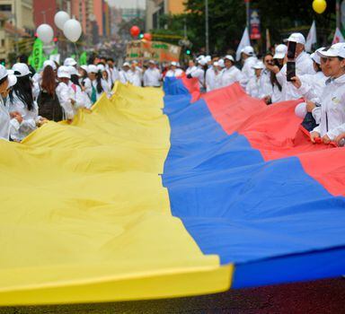 Colombianos protestam em Bogotá contra o presidente Iván Duque usando roupa branca e segurando uma grande bandeira do país