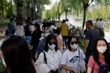 Pessoas usando máscaras faciais aproveitam o clima ao ar livre em um parque durante feriado do Dia do Trabalho em Pequim.