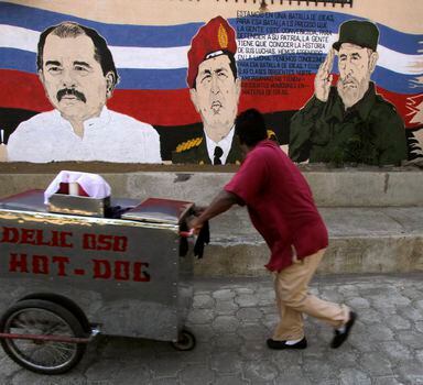 A street vendor pushes his cart past a mural depicting Venezuela's late President Hugo Chavez (C), Cuba's former leader Fidel Castro and Nicaragua's President Daniel Ortega (L), in Managua March 6, 2013. Chavez died on Tuesday at 58 after a two-year battle with cancer that was first detected in his pelvis. REUTERS/Inti Ocon (NICARAGUA - Tags: OBITUARY SOCIETY BUSINESS)