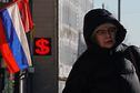 Mulher passa por casa de câmbio na Rússia; país enfrenta escassez de dólares
