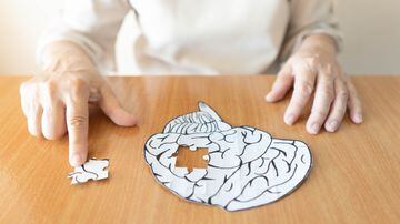 Elderly woman hands putting missing white jigsaw puzzle piece down into the place as a human brain shape. Creative idea for memory loss, dementia, Alzheimer's disease and mental health concept. Foto: Orawan/Adobe Stock 