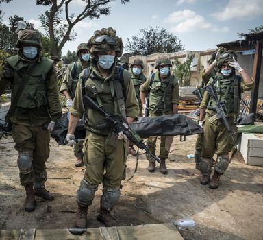 Israeli soldiers carry a body in Kfar Azza, a village just across the border from Gaza that was attacked by Palestinian gunmen, in Israel, Tuesday, Oct. 10, 2023. Israel’s military and espionage services are considered among the word’s best, but on Saturday, operational and intelligence failures led to the worst breach of Israeli defenses in half a century. (Sergey Ponomarev/The New York Times)