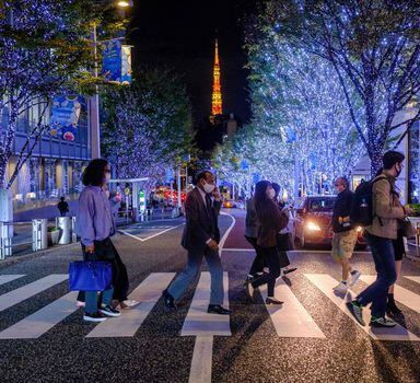 Pessoas cruzam rua próxima à Tokyo Tower