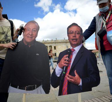 Men pose holding cardboard cartels with images of Colombian presidential left-wing candidate Gustavo Petro (R) and Colombian presidential candidate for the 'Liga de Gobernantes Anticorrupción' party, Rodolfo Hernandez, during a media campaign at Bolivar square in Bogota, on June 9, 2022 - Colombia will hold the presidential election runoff between Bucaramanga's former mayor (2016-2019) Rodolfo Hernandez and leftist Gustavo Petro on June 19, 2022. (Photo by Raul ARBOLEDA / AFP)