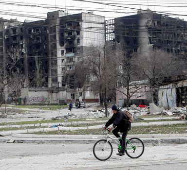 A man rides a bicycle near residential buildings destroyed in the course of Ukraine-Russia conflict in the southern port city of Mariupol, Ukraine April 1, 2022. REUTERS/Alexander Ermochenko