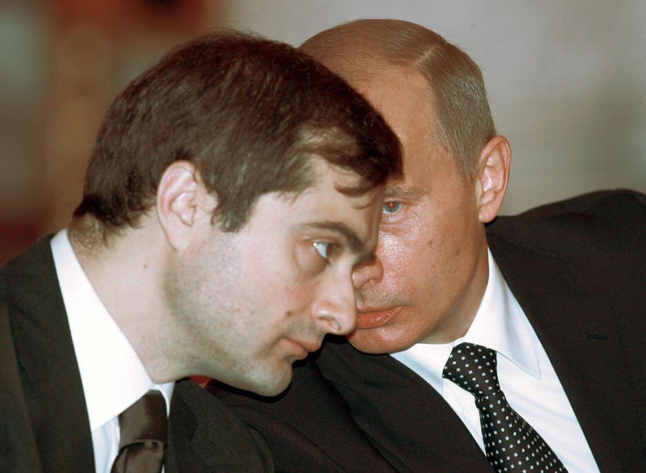 O presidente russo Vladimir Putin, ao fundo, fala com seu braço direito à época, 2019, o político Vladislav 