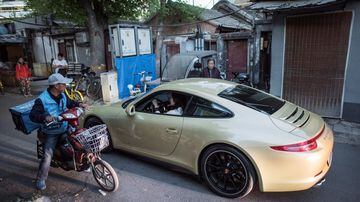 A woman drives her luxuary car in a Hutong. Foto: Fred Dufour