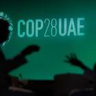 FILE - People are silhouetted against a logo for the COP28 U.N. Climate Summit, Nov. 29, 2023, in Dubai, United Arab Emirates. (AP Photo/Rafiq Maqbool, File)