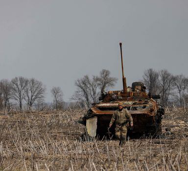 Soldado ucraniano caminha ao redor de um tanque russo queimado nos arredores de Kiev