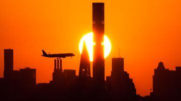 Sol se põe atrás em Manhattan enquanto um avião se aproxima para pousar no Aeroporto LaGuardia, em Nova York.