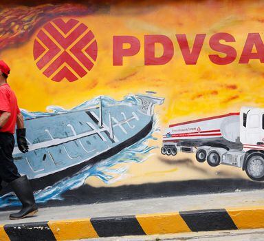 A worker walks past a mural with a PDVSA logo at its gas station in Caracas August 29, 2014. Venezuela's state-run PDVSA has put on hold its plans to export diluted crude oil (DCO) in October as the company reviews production costs that have risen on imports of costly naphtha that it uses to mix with its extra heavy crude, traders told Reuters on Friday. REUTERS/Carlos Garcia Rawlins (VENEZUELA - Tags: ENERGY POLITICS BUSINESS LOGO)