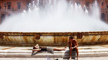 Turistas se refrescam na fonte Plaza de España, em Sevilha, na Espanha, durante uma forte onda de calor que atinge a região. Foto: Jon Nazca / Reuters
