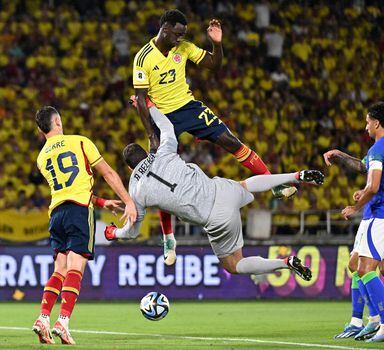 TOPSHOT - Brazil's goalkeeper Alisson (C-bottom) and Colombia's defender Davinson Sanchez (C) fight for the ball during the 2026 FIFA World Cup South American qualification football match between Colombia and Brazil at the Roberto Melendez Metropolitan Stadium in Barranquilla, Colombia, on November 16, 2023. (Photo by Juan BARRETO / AFP)
