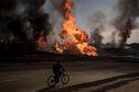 FILE - A man rides his bike past flames and smoke rising from a fire following a Russian attack in Kharkiv, Ukraine, on March 25, 2022. With its aspirations for a quick victory dashed by a stiff Ukrainian resistance, Russia has increasingly focused on grinding down Ukraineâ€™s military in the east in the hope of forcing Kyiv into surrendering part of the countryâ€™s eastern territory to end the war. If Russia succeeds in encircling and destroying the Ukrainian forces in Donbas, the countryâ€™s industrial heartland, it could try to dictate its terms to Kyiv -- and possibly attempt to split the country in two. (AP Photo/Felipe Dana)