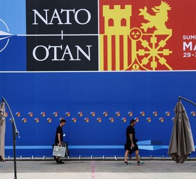 Technicians from TV walk past a poster announcing the NATO Summit inside the Madrid Fair before a NATO summit in Madrid, Spain, June 27, 2022. Nacho Doce/ REUTERS