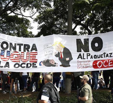 Colombianos protestam com cartaz no qual o presidente Iván Duque aparece como subserviente a Donald Trump