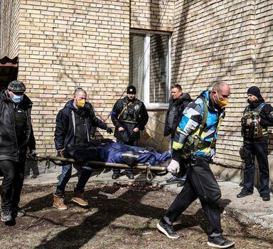 A body is carried at a school in Bucha, northwest of the Ukrainian capital Kyiv on April 4, 2022. - The EU said on April 4, 2022, it is urgently discussing a new round of sanctions on Russia as it condemned "atrocities" reported in Ukrainian towns that have been occupied by Moscow's troops. Russia invaded Ukraine on February 24, 2022. (Photo by RONALDO SCHEMIDT / AFP)