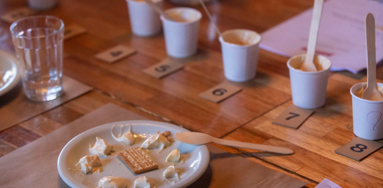 Copinhos brancos de papel preenchidos com maionese sobre mesa de tampo de madeira. Foto: TABA BENEDICTO