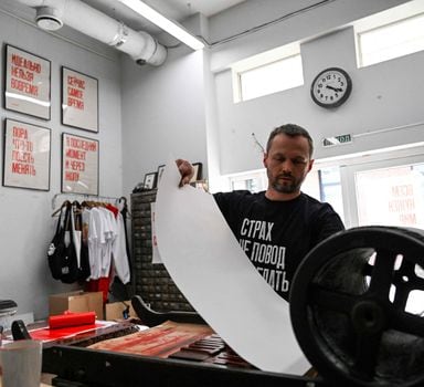 Sergei Besov, the 45-year-old artist and the Partisan Press poster workshop founder, wearing a black T-shirt with a slogan reading "Fear is no reason not to act" makes a poster using an old manually-operated printing press in his workshop in Moscow on June 1, 2022. (Photo by Kirill KUDRYAVTSEV / AFP)