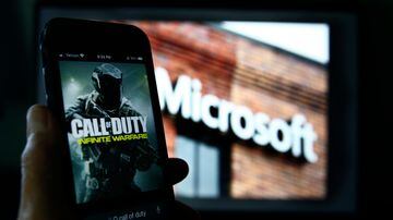 FILE - An image from Activision's Call of Duty is shown on a smartphone near a photograph of the Microsoft logo in this photo taken in New York, June 15, 2023. Microsoft’s purchase of video game maker Activision Blizzard won final approval Friday, Oct. 13, from Britain’s competition watchdog, reversing its earlier decision to block the $69 billion deal and removing a last obstacle for one of the largest tech transactions in history. (AP Photo/Peter Morgan, File). Foto: Peter Morgan/AP Photo 