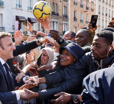 French President and La Republique en Marche (LREM) party candidate for re-election Emmanuel Macron(L) holds hands of inhabitants during a campaign visit in Saint-Denis, a northern suburb of Paris, on April 21, 2022. - French voters head to the polls on April 24, 2022 for the second round of France's presidential election. (Photo by Ludovic MARIN / POOL / AFP)