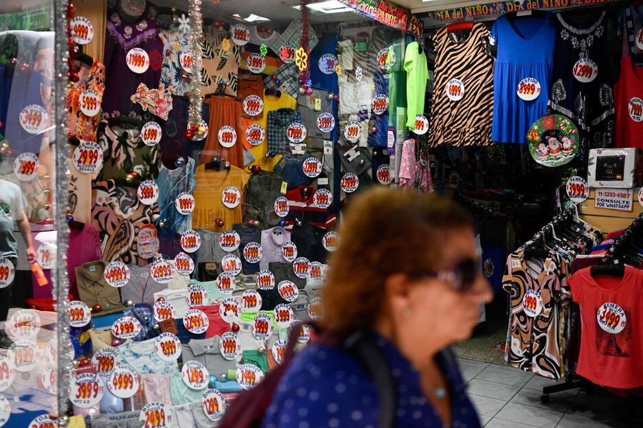 Mulher caminha diante de roupas com etiquetas de preço em Buenos Aires, em imagem do dia 5. Preços devem crescer no país com medidas do novo governo
