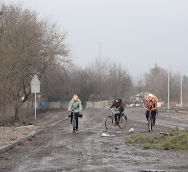 Moradores andam de bicicleta por ruas do vilarejo Nova Basan, em Kiev, após saída de soldados russos